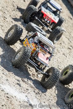 four toy trucks are on the ground with their wheels up and one is off road