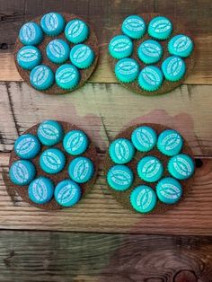 three cupcakes with blue frosting sitting on top of a wooden table