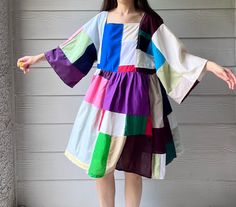 a woman standing in front of a wall wearing a colorful dress