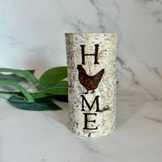 a white birch tree with the word home painted on it and a brown chicken sitting on top