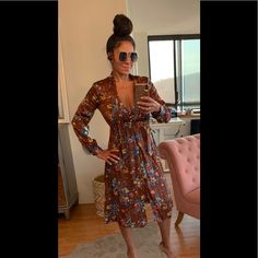 a woman in a floral dress taking a selfie with her cell phone while wearing sunglasses