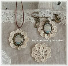 three pieces of jewelry sitting on top of a lace covered table cloth next to each other