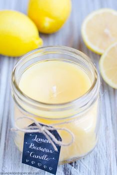 a jar filled with lemon essential candle next to sliced lemons