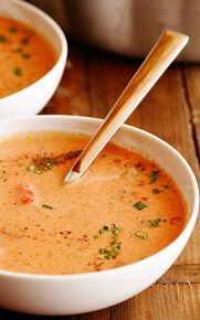 two white bowls filled with soup on top of a wooden table