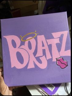 someone holding up a purple box with the word braz painted on it in pink and gold