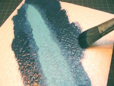 a brush is being used to paint a piece of paper with blue and white frosting