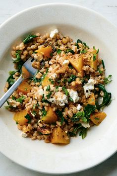 a white bowl filled with rice, spinach and other food on top of a table