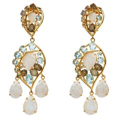 The Cara Earrings, crafted from semi-precious stones, feature a detachable bottom, offering a versatile option for a simpler style. Inspired by vintage designs. SKU: ED-3D-119 Stones: Labradorite, Blue Topaz & Moonstone Material: 14K Gold Plated Dimensions: 3 1/2" X 1 1/4" Semi Precious Stones, Vintage Jewels, Clear Quartz, Blue Topaz, Semiprecious Stones, Post Earrings, Precious Stones, Statement Earrings, Moonstone