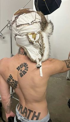 a man with tattoos on his back wearing a mask