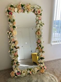 a mirror that has flowers on it in the middle of a room next to a rug