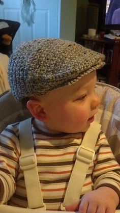 a small child wearing a hat and sitting in a highchair looking at something