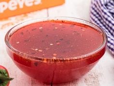 a red sauce in a glass bowl next to tomatoes