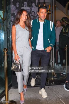 a man and woman are walking out of a building with their hands in each others'pockets