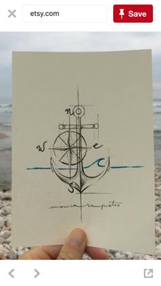 a sign with an anchor on it sitting in front of the water and rocks at the beach