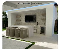 an outdoor kitchen and living area with white walls, concrete floors and large screen tv mounted on the wall