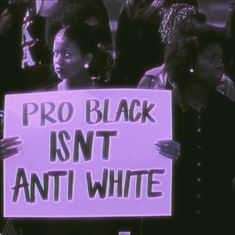 two women holding up a sign that says pro black isn't anti - white