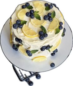 a cake with lemons, blueberries and mint leaves on it sitting on a plate