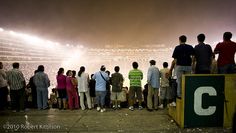 a group of people standing on top of a field next to a stadium filled with fans