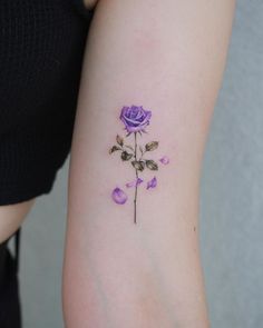 a purple rose tattoo on the left arm