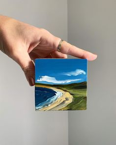 a hand holding up a piece of paper with an image of a beach on it