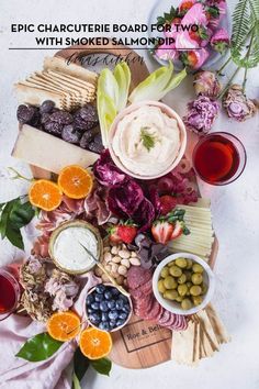 an assortment of cheeses, meats and fruit on a platter with flowers