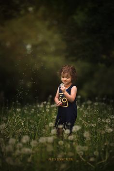 a little boy standing in the middle of a field with dandelions around him