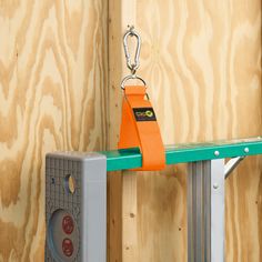 an orange safety device is hanging on a green shelf in front of wood paneling