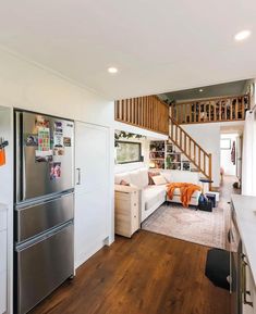 a living room with a couch, refrigerator and stairs leading to the upper floor area