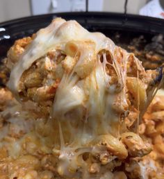 a spoon full of cheese and meat casserole being lifted from a skillet