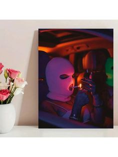 a vase filled with pink roses next to a photo of a person in a white mask