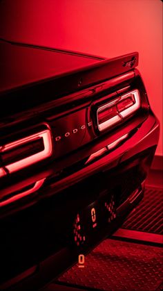 the tail light of a modern car is red and there are numbers on the grille