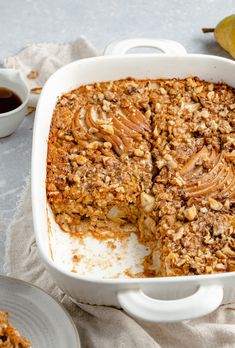 a casserole dish filled with apple crumble toppings next to a cup of coffee