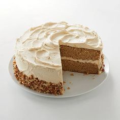 a cake with white frosting on a plate next to a slice missing from it