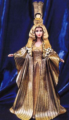 the doll is dressed in gold and has an elaborate headpiece