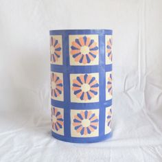 a blue and orange vase sitting on top of a white sheet