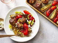 a white plate topped with meat and veggies next to a tray of food