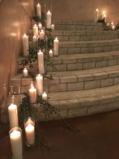 candles are lined up on the steps in front of some stairs with ivy and greenery