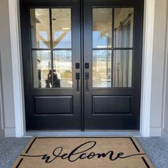 a welcome mat with the words welcome on it in front of a black double door