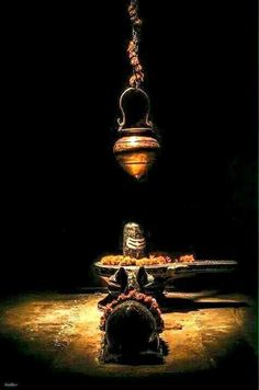 an oil lamp hanging from a chain in the middle of a dark room with food on it