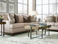 a living room scene with focus on the couch and coffee table in front of large windows