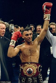 a man holding up his boxing gloves in the middle of a crowded room with other people