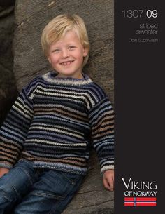 a young boy sitting on top of a rock wearing a striped sweater and blue jeans