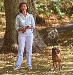 a woman standing next to a brown dog