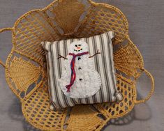 a snowman pillow sitting on top of a wicker chair