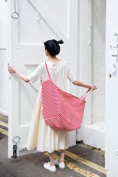 a woman carrying a red and white striped bag