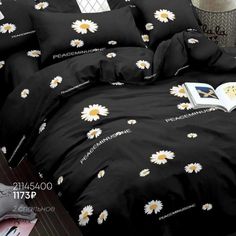 a black comforter with white daisies on it and an open book in the foreground