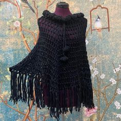 a black crocheted shawl on a mannequin next to a tree