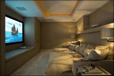 a home theater with couches and a flat screen tv on the wall in front of it