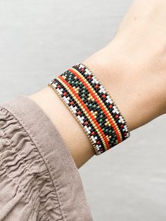 a woman's arm wearing a bracelet with multicolored seed beaded beads