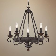 an iron chandelier with five candles hanging from the bottom and four lights on each side